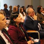 Grupa ludzi siedzi na sali konferencyjnej, skupieni podczas prezentacji.