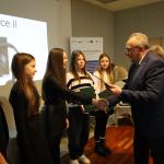 Mężczyzna wręcza dyplom młodej dziewczynie podczas ceremonii wręczenia nagród.