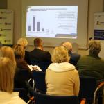 Kobieta prowadzi prezentację przed grupą osób w sali konferencyjnej.