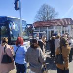 grupa ludzi stojąca przy autokarze w słoneczny dzień
