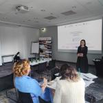 prelegent wygłaszający referat obok wyświetlanego slajdu na kolorowym tle 