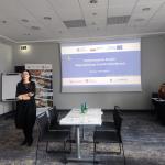 prelegent wygłaszający referat obok wyświetlanego slajdu na kolorowym tle 