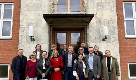 Grupa ludzi stoi przed wejściem do budynku z czerwonej cegły.