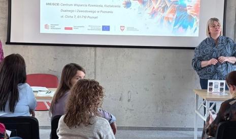Kobieta prowadzi prezentację przed grupą słuchaczy w sali konferencyjnej.